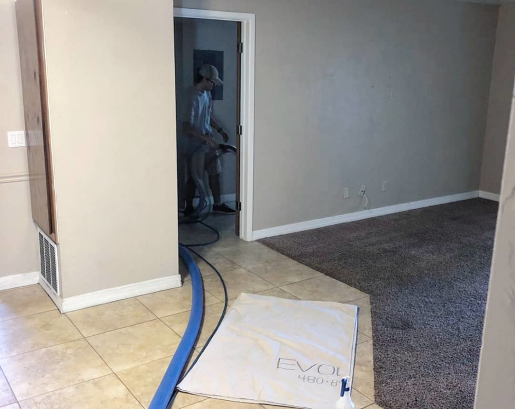 A technician cleaning carpet with professional equipment and hoses at Evolution Carpet Cleaning in Fresno, CA