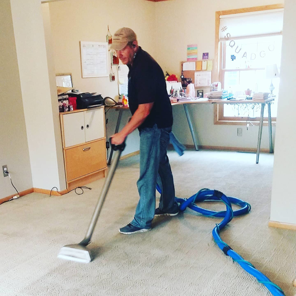 A technician professionally cleaning a carpet with a cleaning wand and hose for Green Planet Carpet Cleaning in Bloomington, MN.