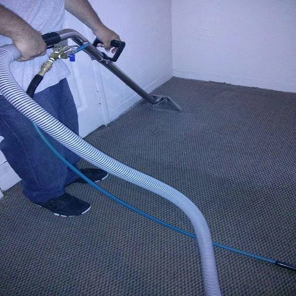 A professional technician cleaning a grey carpet with a specialized wand from Pro Carpet Solutions Carpet Cleaning in Allentown, PA.
