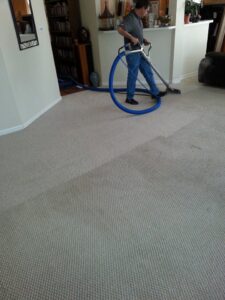 A technician from Steam Solutions Carpet Cleaning operating a professional cleaning wand on a light-colored carpet in San Antonio, TX.