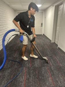 A technician from Inlet Carpet Care cleaning a carpeted hallway in Virginia Beach, VA