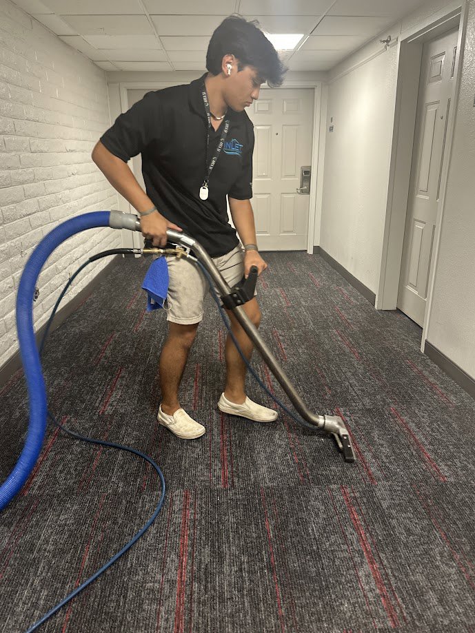 A technician from Inlet Carpet Care cleaning a carpeted hallway in Virginia Beach, VA