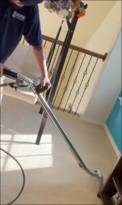 A technician from 5 Sons Carpet Cleaning using a cleaning wand on a carpeted staircase in Dallas, TX