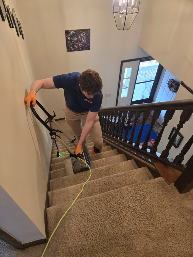 A technician professionally cleaning carpeted stairs with specialized equipment for Ohana Clean llc in Saint Paul, MN