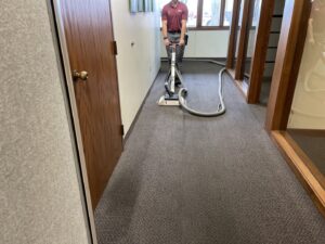 A KODA Carpet Cleaning technician operating a professional carpet cleaning machine in a commercial hallway in Holland, MI.