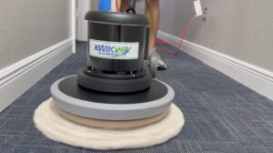 A technician from Rhode Island Kwik Dry operating a rotary carpet cleaning machine on commercial carpet in a hallway in Rhode Island.