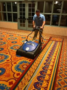 A technician operating a carpet cleaning machine on a large commercial carpet at Strategic Carpet Clean in Winter Park, Orlando, FL