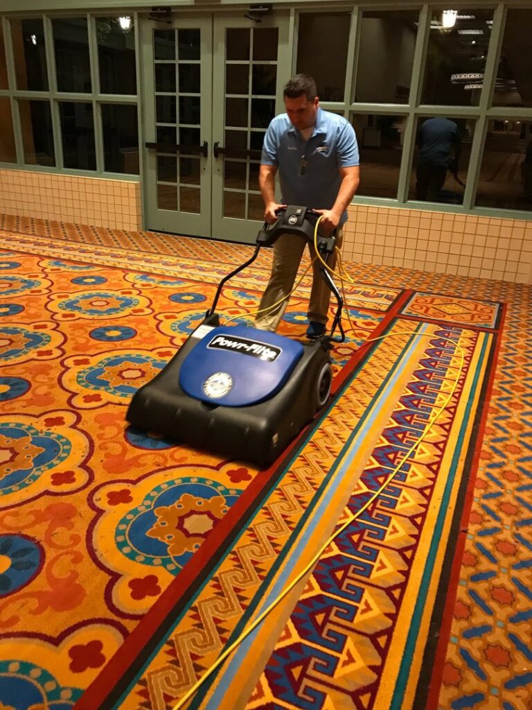 A technician operating a carpet cleaning machine on a large commercial carpet at Strategic Carpet Clean in Winter Park, Orlando, FL