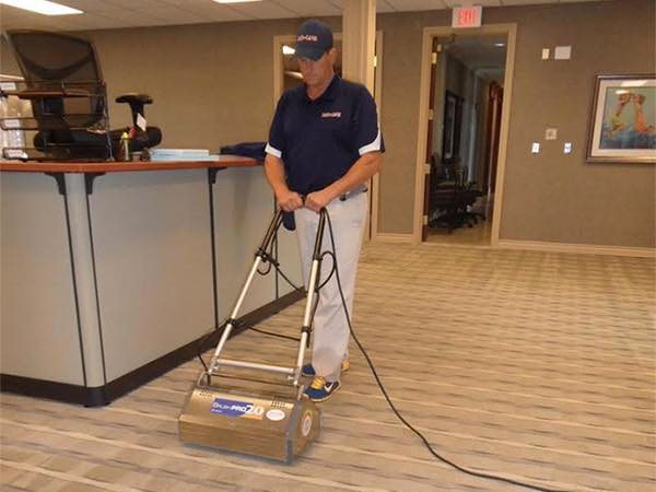 A technician cleaning commercial office carpet with a rotary machine for Duo-Care Cleaning and Restoration in Sterling Heights, MI
