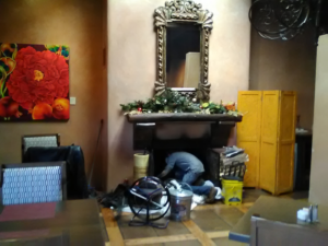 A K-West NM technician performing a thorough chimney sweep and cleaning inside a fireplace in Santa Fe, NM.