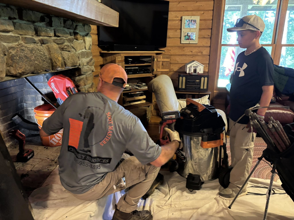 A Soot Masters Chimney Service LLC technician cleaning a fireplace with a vacuum in a home in Jackson, MS.