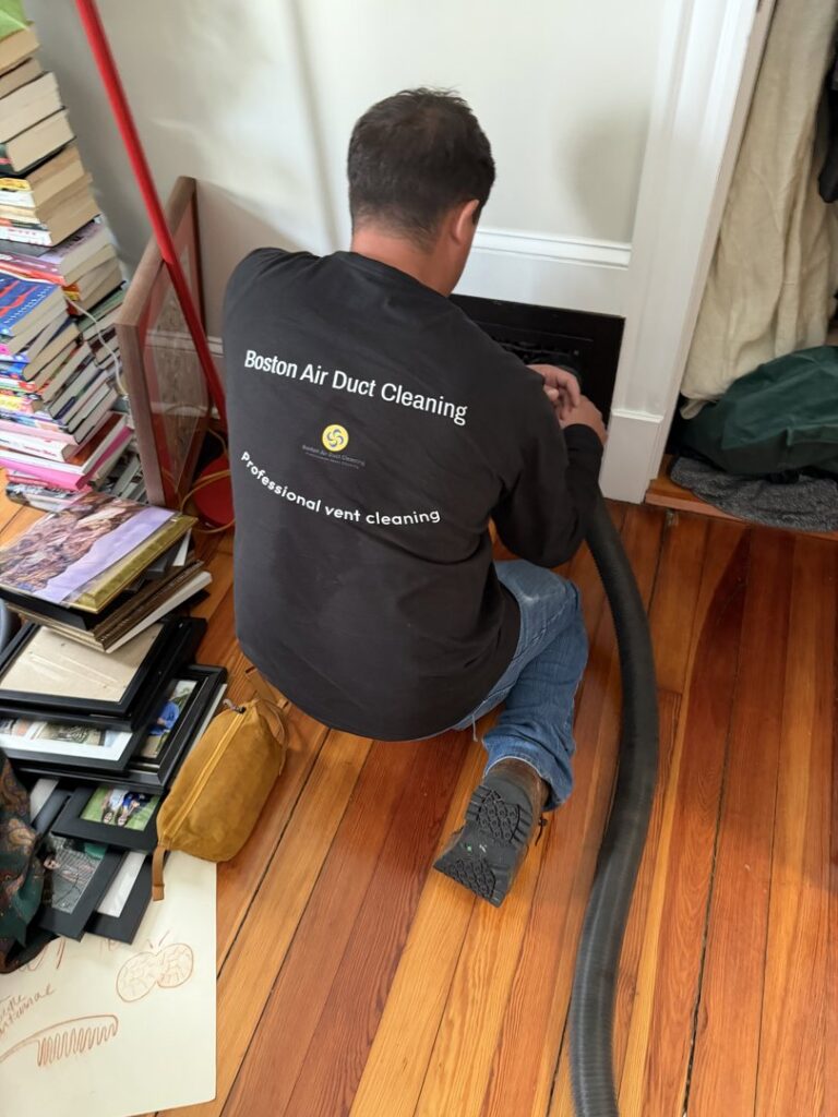 A technician from Boston Air Ducts Cleaning cleaning a floor air vent in a residential home in Newton, MA.