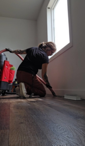 A technician cleaning a floor vent with a powerful vacuum system, performed by Aero Brush Duct Cleaning in Billings, MT.