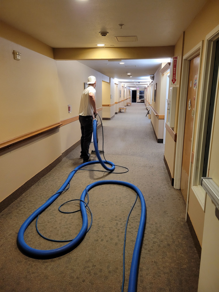 A technician from Interior Care Carpet Cleaning cleaning a long hallway carpet with professional equipment in Bend, OR.
