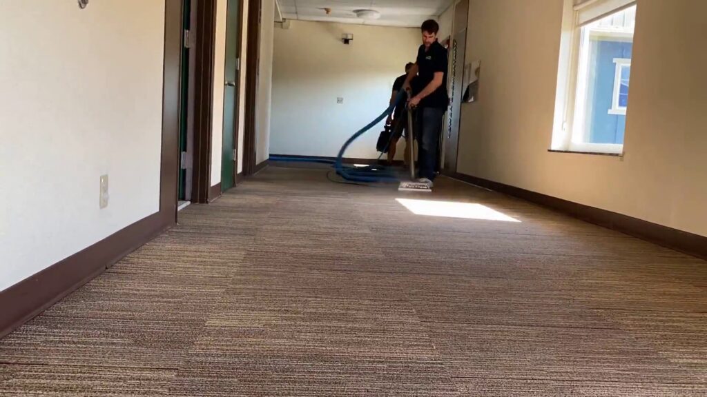 A professional technician cleaning a hallway carpet with specialized equipment for Pacific Steam Carpet Cleaning in Gresham, OR.
