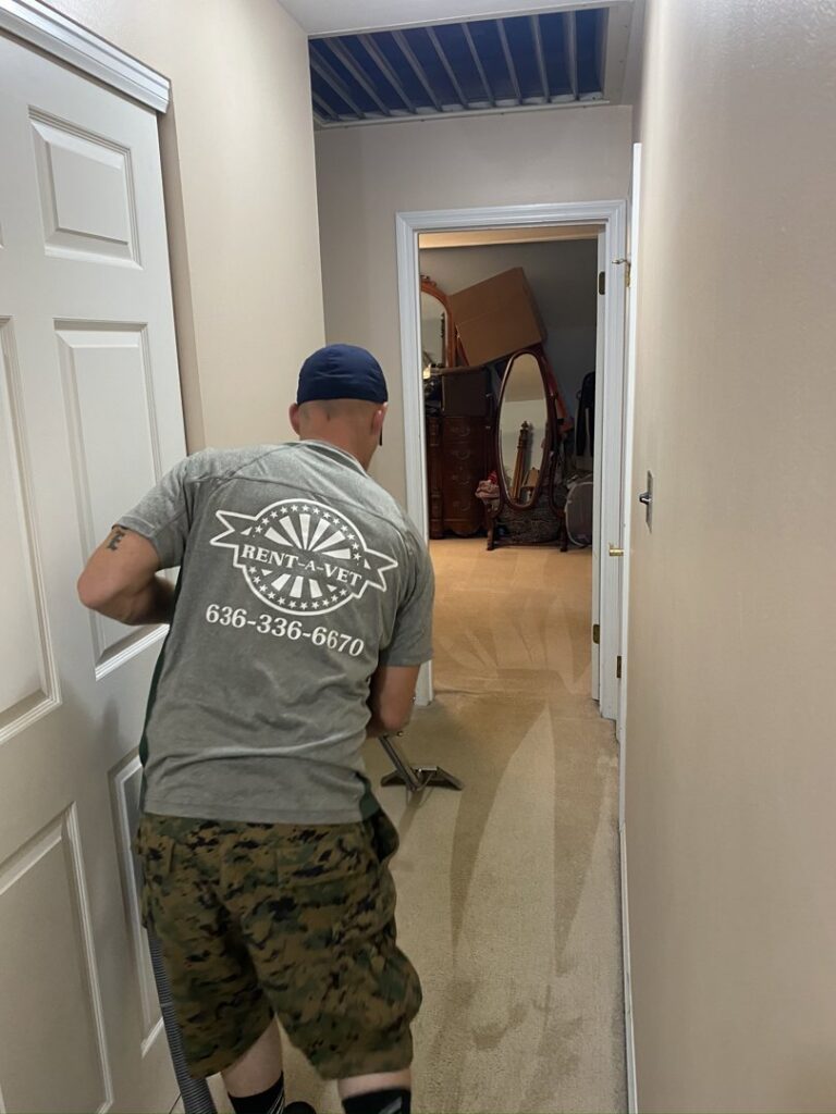 A Rent A Vet Carpet Cleaning technician cleaning a hallway carpet with a wand in St. Charles, MO.