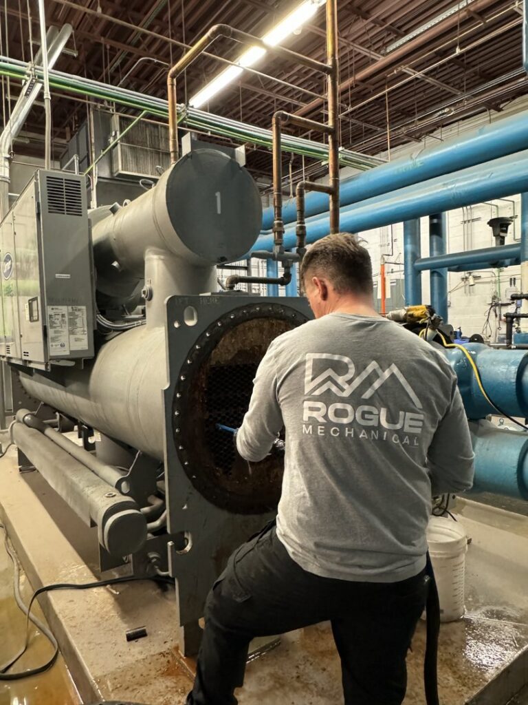 A technician cleaning an industrial chiller or boiler system for Rogue Mechanical in Las Vegas, NV.