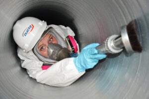 A technician in a hazmat suit and respirator cleaning a large HVAC duct for Ductz of Southeast Michigan in Livonia, MI.