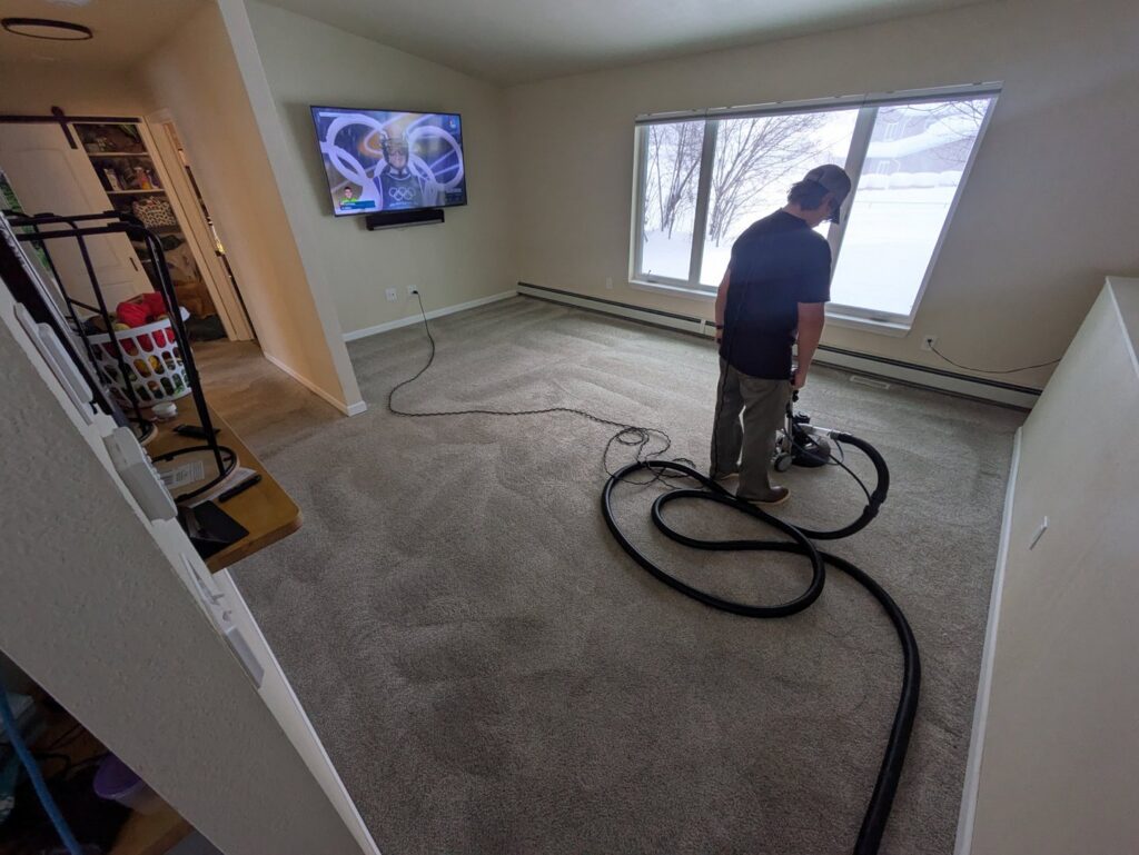 A technician from Alaska Floor Care Specialists cleaning living room carpet with a professional machine in Fairbanks, AK.