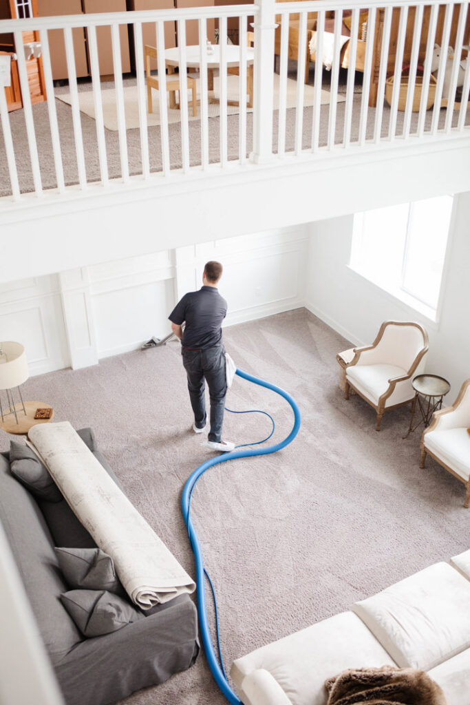 A Zerorez Greenville, SC technician cleaning a large living room carpet from an elevated view.