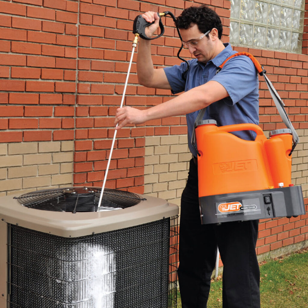 A technician cleaning an outdoor air conditioning unit during maintenance by R&B Cooling&Heating in Abbeville, LA.