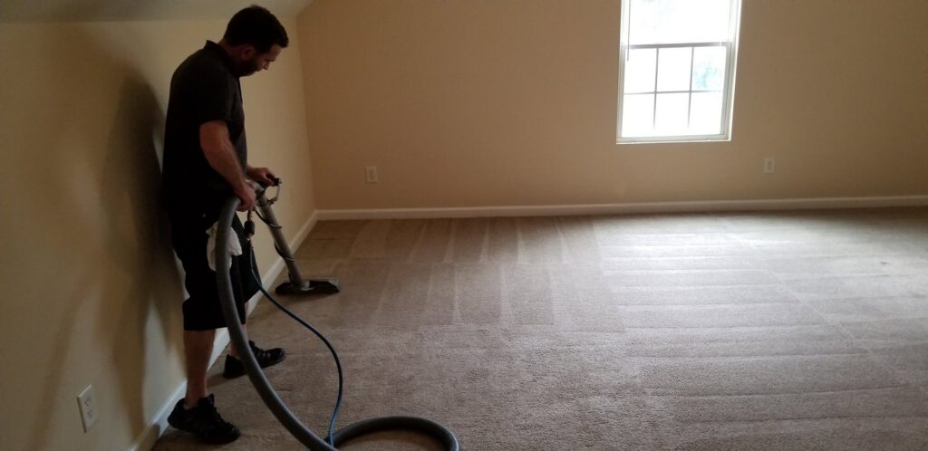 A professional technician cleaning a residential carpeted room with a cleaning wand for Steam Giant in Raleigh, NC.