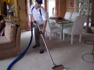 A technician cleaning residential living room carpet with a professional wand for Duo-Care Cleaning and Restoration in Sterling Heights, MI