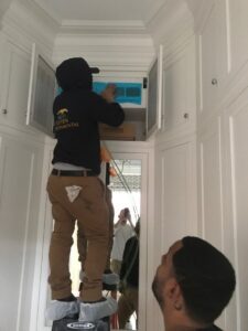 An Aspen Air Duct Cleaning technician on a ladder cleaning a residential air vent in Methuen, MA.
