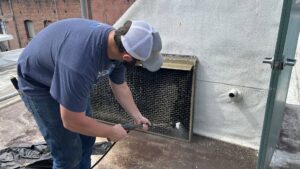 A technician pressure washing a large commercial HVAC unit on a rooftop, performed by Service Kings Heating and Air in Jamestown, ND.