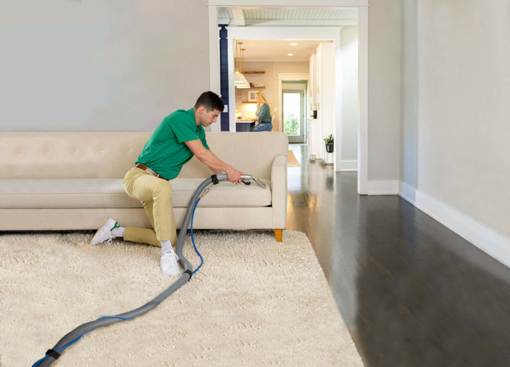 A Precision Chem-Dry Of DFW technician professionally cleaning a sofa and rug in a home in North Richland Hills, TX.