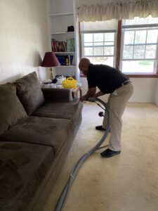 A technician performing upholstery cleaning on a sofa for Rent A Vet Carpet Cleaning in St. Charles, MO.