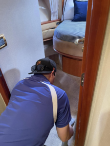 A Service Kings Home Services technician cleaning carpet inside a yacht cabin in San Diego, CA.