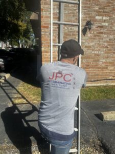 A JPC Exterminating, LLC technician climbing a ladder for an exterior inspection of a building in New Orleans, LA.