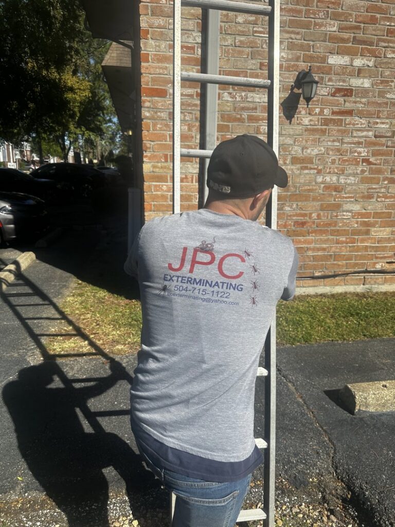 A JPC Exterminating, LLC technician climbing a ladder for an exterior inspection of a building in New Orleans, LA.