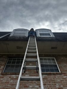 A JPC Exterminating, LLC technician climbing a ladder to inspect a roof for pest entry points in New Orleans, LA.