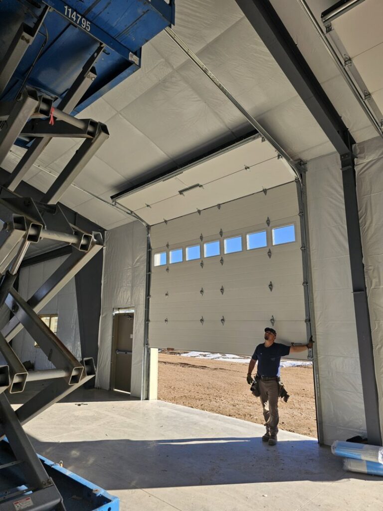 A Prutch's Garage Door technician inspecting a large commercial garage door installation in Colorado Springs, CO