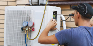 A technician connects gauges to an outdoor AC unit during service for BV Air Conditioning & Heating in Dallas, TX.