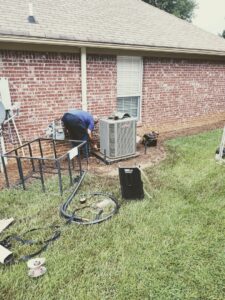 A technician connecting refrigerant gauges to an outdoor AC unit for Comfortech-Service Experts Jackson in Jackson, MS