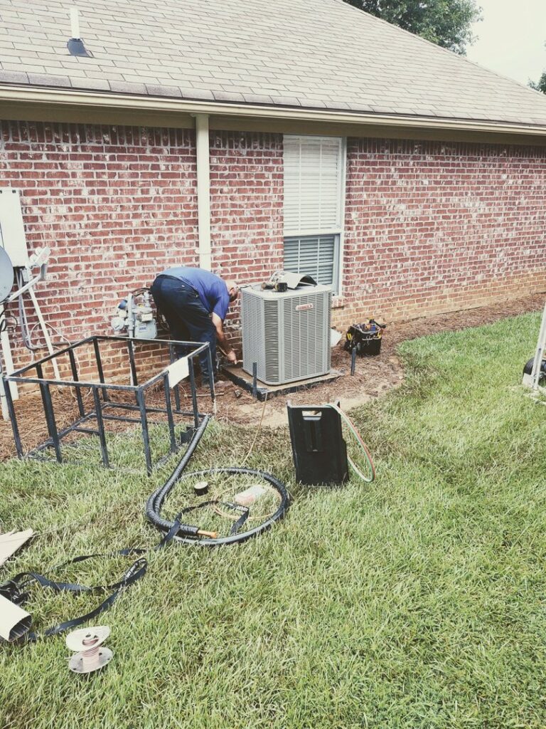 A technician connecting refrigerant gauges to an outdoor AC unit for Comfortech-Service Experts Jackson in Jackson, MS