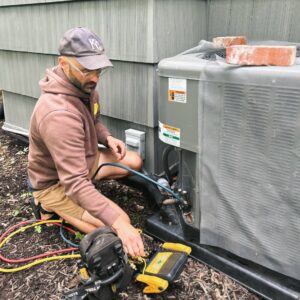 A skilled technician from Davis Heating, Air Conditioning & Home connecting gauges to an outdoor AC unit for service in Overland Park, KS.