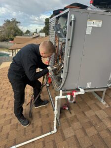 A technician connecting refrigerant lines on a rooftop HVAC unit during installation by 365 Mechanical in Mesa, AZ.
