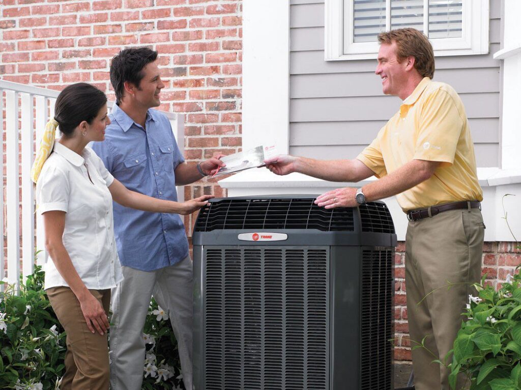 A technician consulting with customers next to an outdoor HVAC unit from Absolute Comfort Heating & Cooling, Inc. in Virginia Beach, VA.