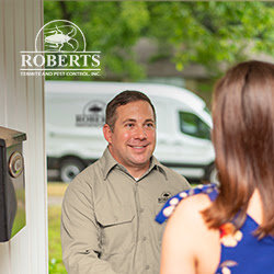 A pest control technician consulting with a customer at their home for Roberts Termite & Pest Control in Austin, TX