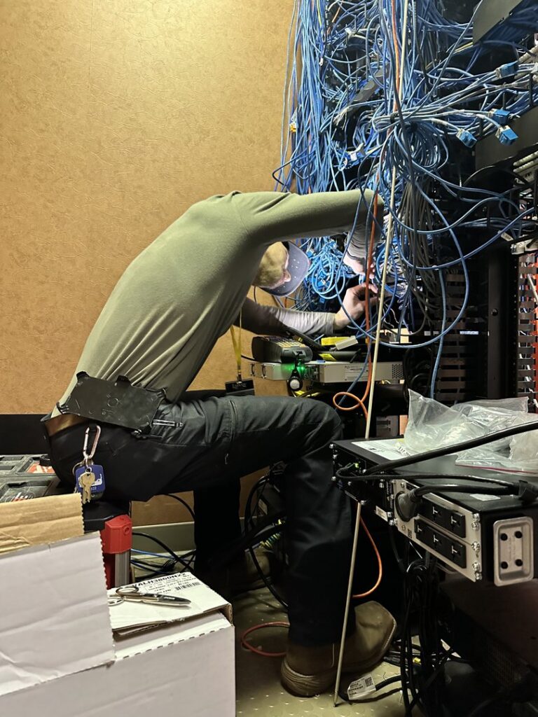 A technician performing data cabling and wiring work in a complex server rack for Babcock Electric & Communications in Lake Charles, LA.