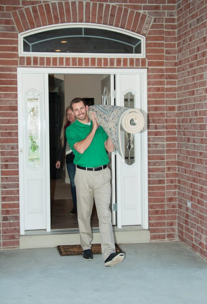 A Chem-Dry technician delivering a freshly cleaned area rug to a customer's home in Seattle, WA