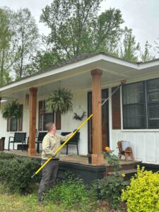 A Diamond Pest Solutions technician in Conway, AR, de-webbing the porch eaves of a residential home as part of pest control.