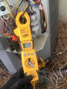 A technician using a clamp meter to diagnose an outdoor HVAC unit at Parks Heating Cooling Plumbing & Electrical in Indian Trail, NC