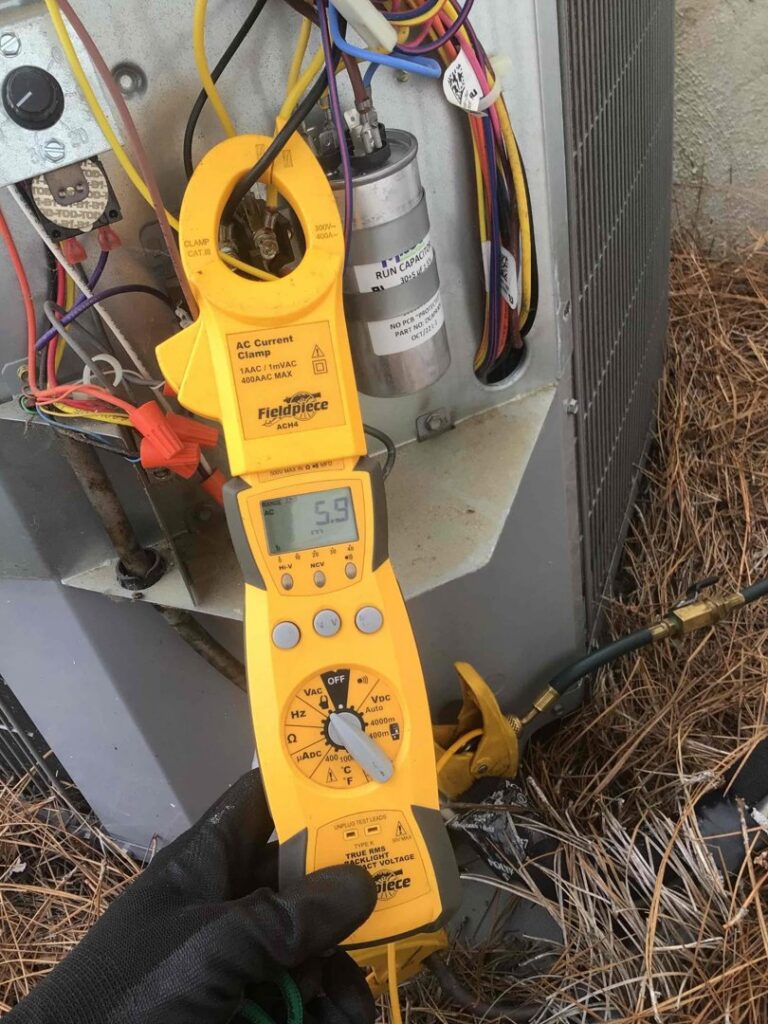 A technician using a clamp meter to diagnose an outdoor HVAC unit at Parks Heating Cooling Plumbing & Electrical in Indian Trail, NC