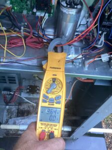 A technician diagnosing an HVAC unit with a multimeter for Integrity Services Heating and Cooling in Madison, AL.