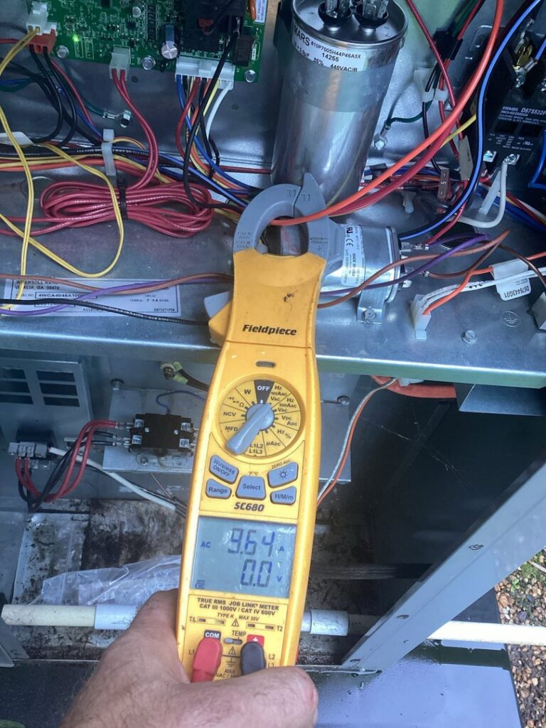 A technician diagnosing an HVAC unit with a multimeter for Integrity Services Heating and Cooling in Madison, AL.